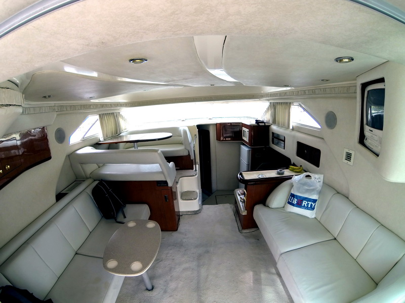 Amplio salón del Sea Ray 44 con sillones de piel blanca, mesa de comedor, cocineta y acabados de madera cálida