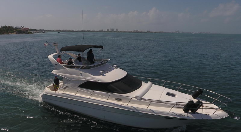 41 ft Sea Ray flybridge yacht cruising turquoise Caribbean waters off Cancun Hotel Zone with guests on the upper deck charter