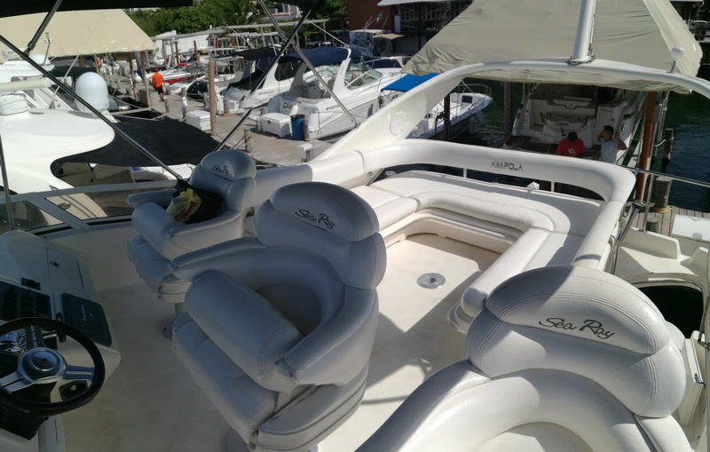 Flybridge of Sea Ray 41 Amapola with white helm seats and U-shaped lounge docked at a Cancun marina, luxury yacht charter