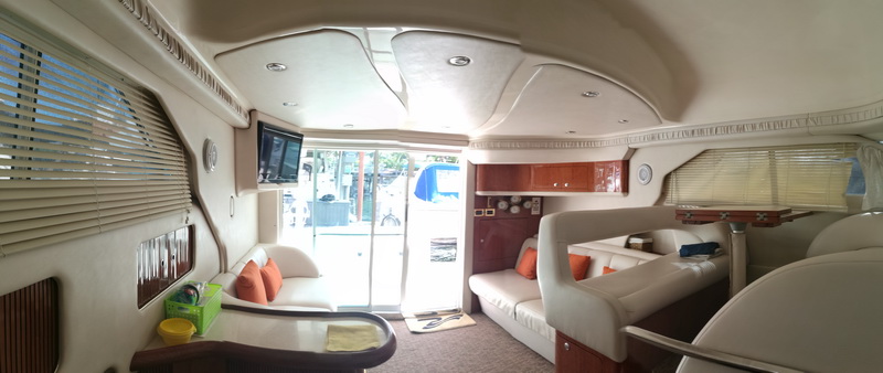 Panoramic interior view of 41 ft Sea Ray flybridge yacht salon with seating, TV and aft deck access on Cancun yacht rental