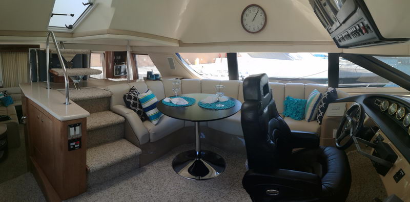 Carver 55 ft yacht interior with helm station, circular dining table, curved staircase and main lounge seating area