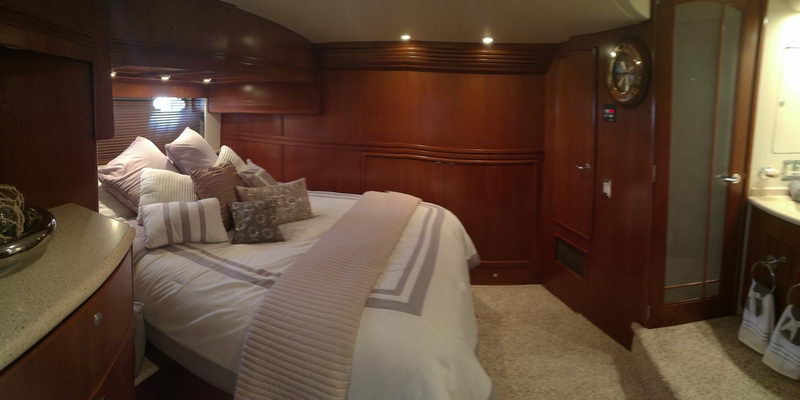 Luxury master cabin aboard Carver 55 ft yacht in Cancún featuring king bed and polished dark wood paneling throughout