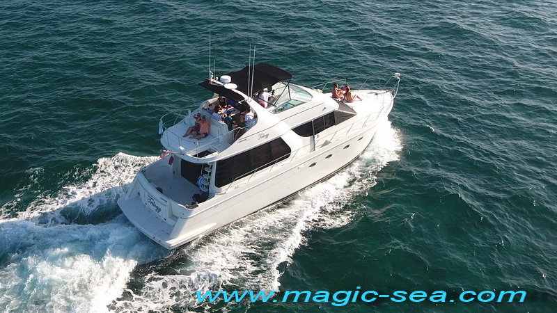 Aerial view of Carver 55 ft luxury motor yacht underway on open blue Caribbean sea near Cancún with guests on sundeck
