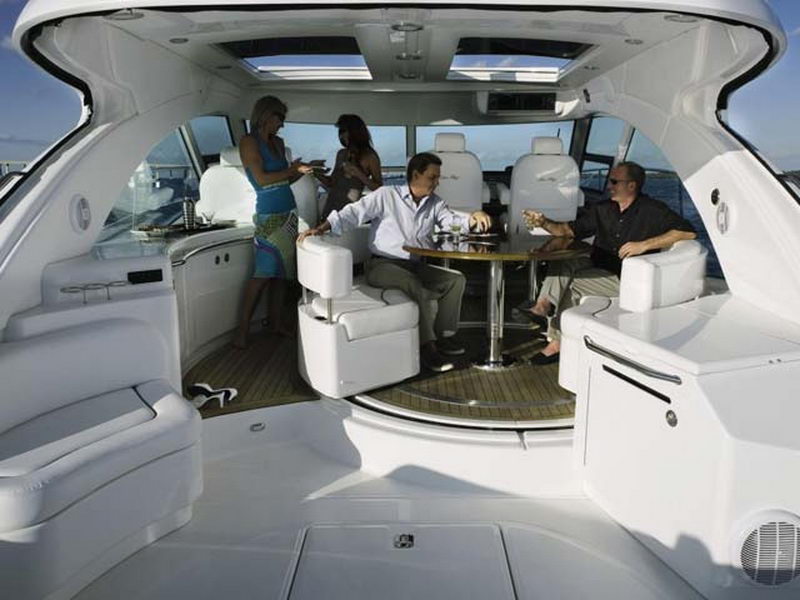 Guests enjoying cocktails in the open cockpit lounge of the 55 ft Sea Ray under its panoramic sunroof, luxury yacht rental Cancun