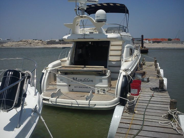 Stern of Sealine 55 ft group charter yacht Mandilon moored at wooden dock with teak swim platform and boarding ladder