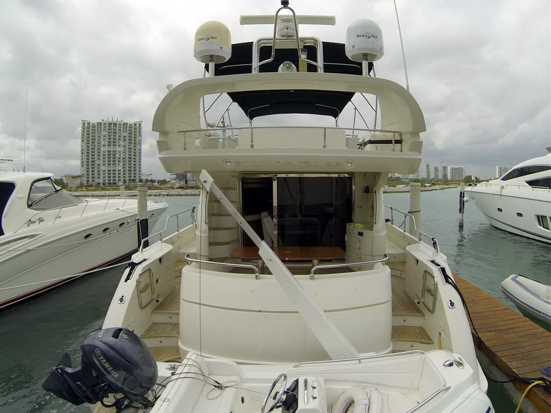 Stern view of Nuvaris 63 ft charter yacht at marina showing flybridge cockpit, deck and Yamaha tender dinghy