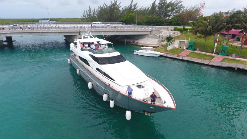 Vista aérea del yate Azimut de 100 pies pasando por el puente de la marina de Cancún con grupos en cubierta