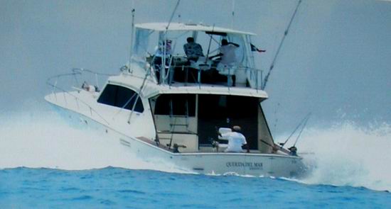 Toma de acción del Hatteras 48 'Querida del Mar' cortando el oleaje del Caribe con pescadores en el flybridge y el cockpit y rocío de agua volando
