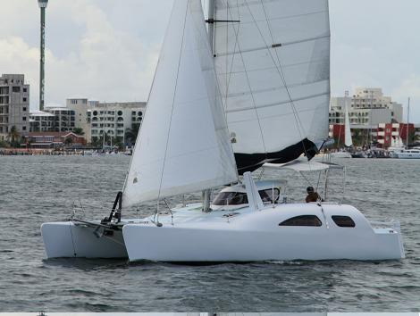 Catamarán de vela Nalgone navegando con velas desplegadas frente a la costa de Cancún sobre el mar Caribe