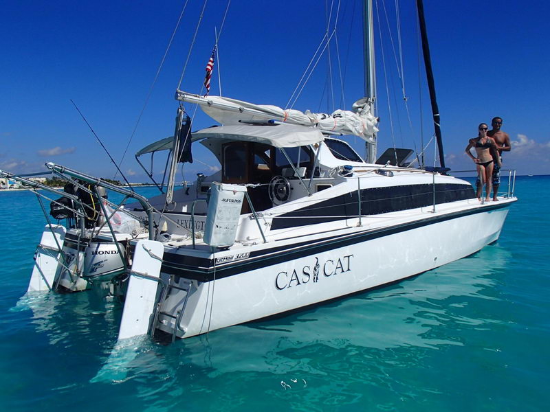 Catamarán de 32 pies Cas Cat fondeado en aguas turquesas de Puerto Aventuras con pareja a bordo, Riviera Maya