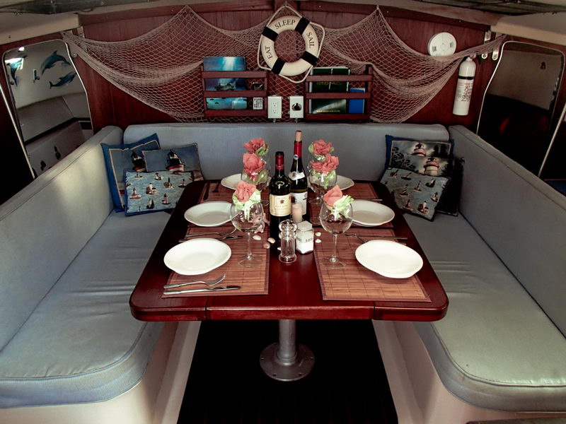 Salón del catamarán de 32 pies con mesa puesta, vino y decoración náutica para una experiencia privada en la Riviera Maya