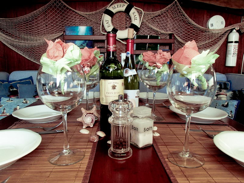Mesa del catamarán decorada con copas de vino, rosas y conchas para una cena romántica a bordo en la Riviera Maya