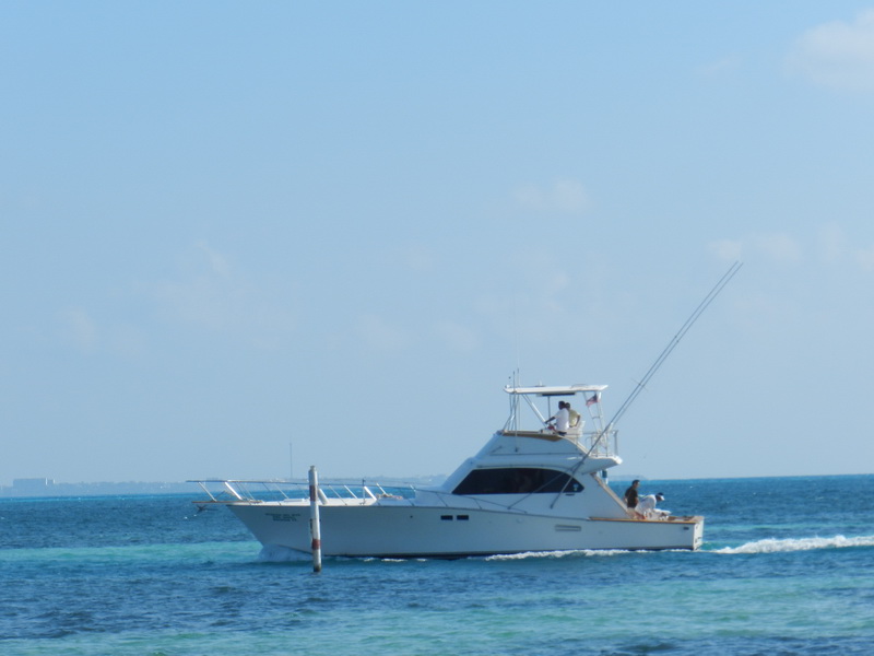 Perfil lateral del Hatteras 48 'Querida del Mar' navegando sobre aguas turquesas del Caribe con un tangón levantado cerca de Cancún