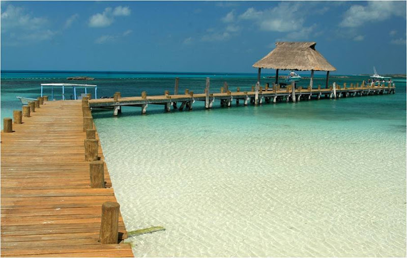 Largo muelle de madera con palapa de techo de palma extendiéndose sobre las aguas someras de arena blanca de Isla Contoy cerca de Cancún