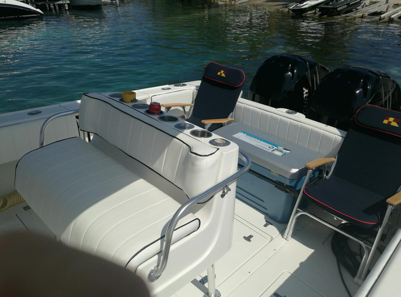Cubierta de popa del Intrepid 32 con asientos acolchados, hielera y dos motores fuera de borda negros listos para un charter de pesca en Cancún