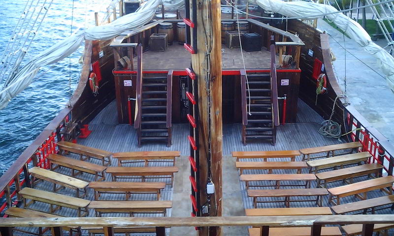 Cubierta de madera abierta del galeón Jolly Roger con bancas alrededor de un escenario central para el show pirata