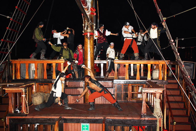 Piratas disfrazados escenificando un duelo de espadas por las cubiertas del galeón Jolly Roger durante el show nocturno