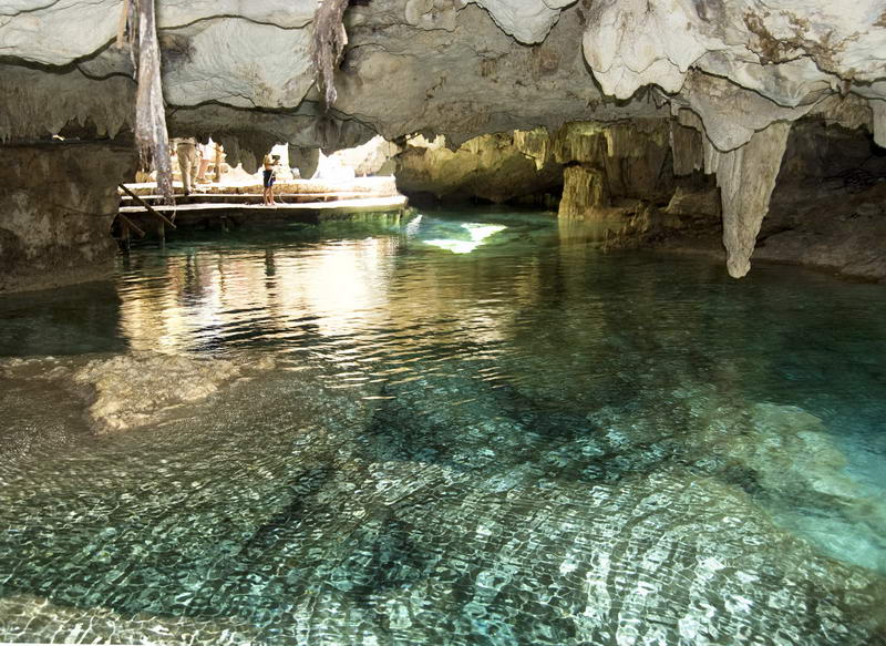 Poza de cenote cristalina enmarcada por antiguas columnas de la cueva en el parque natural Aktun Chen entre Akumal y Xel-Há