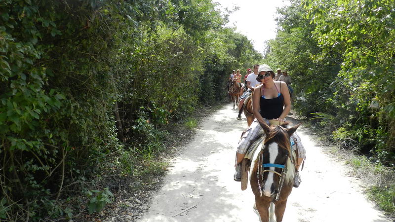 Grupo a caballo por un sendero de selva tropical rumbo a Playa Maroma en la Riviera Maya