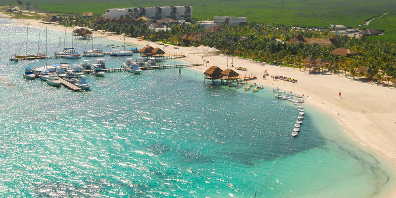 Vista aérea de Marina Maroma con catamaranes y barcos amarrados en los muelles junto a la playa de arena blanca y el Caribe turquesa