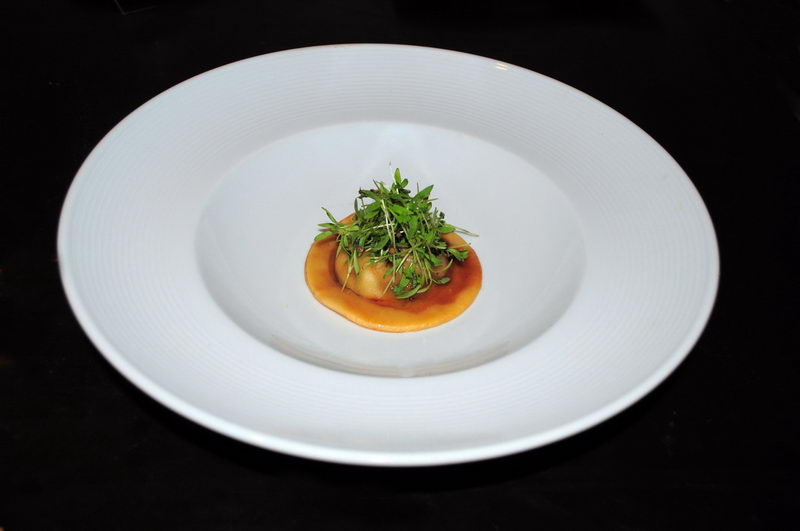 Ravioli individual coronado con microgreens frescos en una salsa ligera, servido en un plato hondo blanco por el servicio gourmet de Maroma
