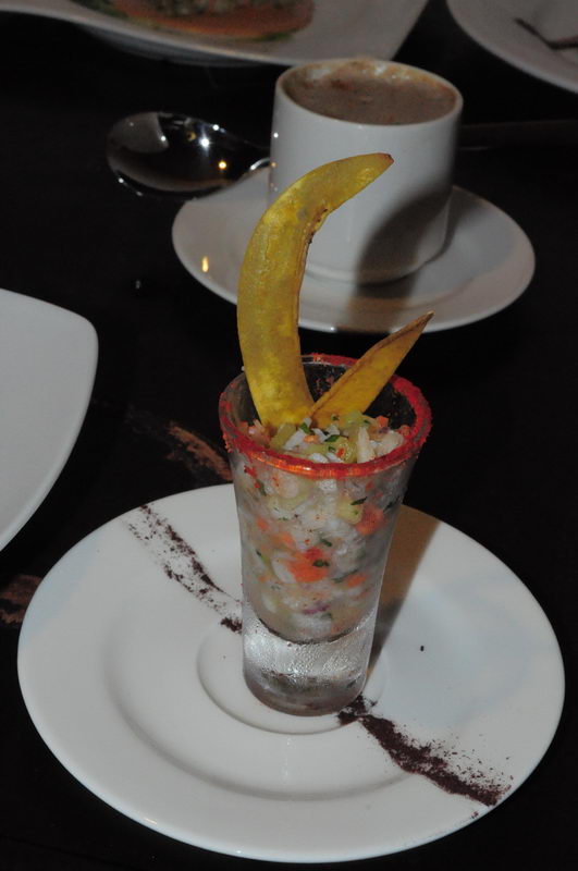 Shot de ceviche fresco decorado con chips de plátano, aperitivo insignia del restaurante frente al mar en Marina Maroma cerca de Cancún