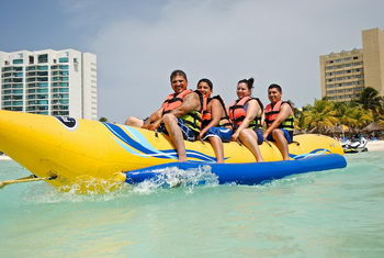 Group riding an inflatable yellow banana boat towed across the Cancun bay for a fun water ride