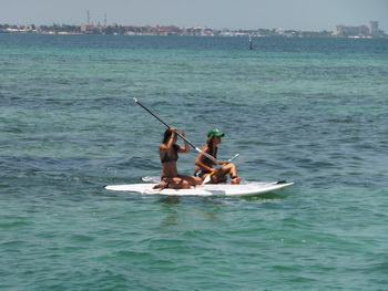 Stand-up paddleboarder gliding across the flat turquoise water of the Cancun bay
