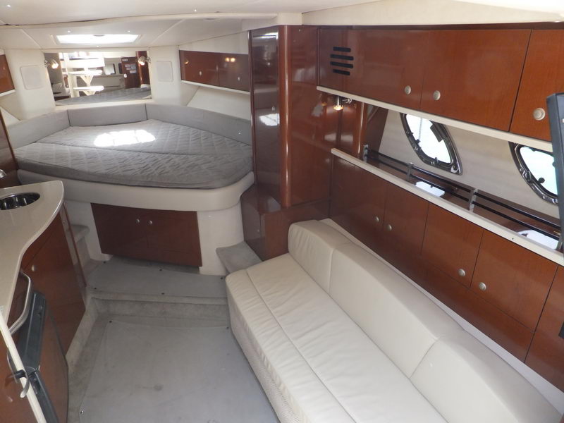Elegante camarote interior del yate SeaRay Sundancer en Cancún con cama doble y sofá de cuero crema en el salón