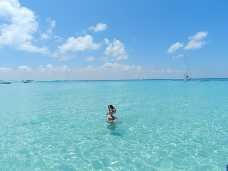 Swimming in crystal clear turquoise Caribbean water near sailboat, Isla Mujeres stop during Cancun sailing charter tour