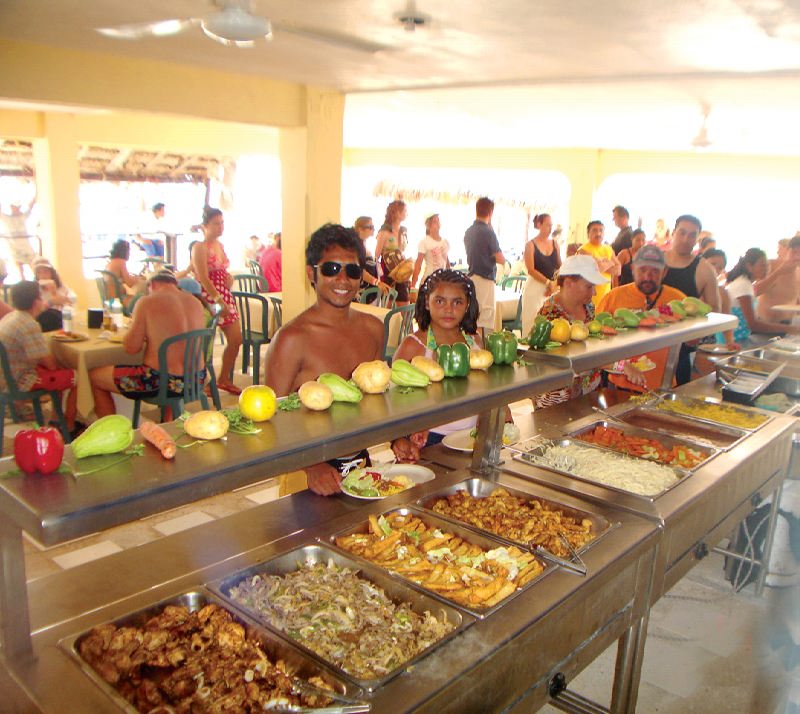 Visitantes relajándose en el beach club de Isla Mujeres durante un tour en catamarán desde Cancún, agua turquesa del Caribe
