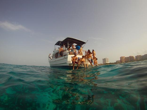 Group of guests enjoying party on Tafil classic wood trawler in turquoise Caribbean waters near Cancun Hotel Zone