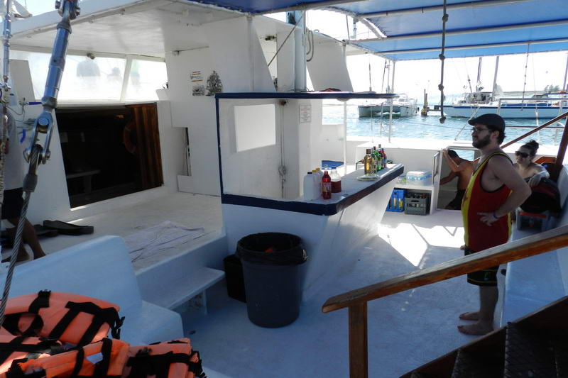 Cubierta sombreada y bar abierto del catamarán Tahuna con chalecos salvavidas apilados, listo para un tour de grupo de vela y snorkel en Maroma Playa del Carmen