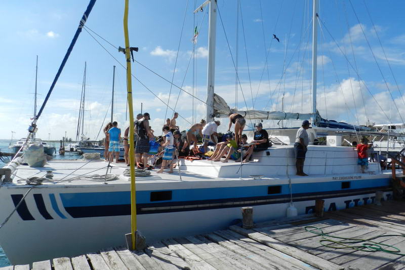 Gran grupo reuniéndose en el catamarán Tahuna amarrado al muelle de Maroma, preparándose para un paseo de grupo en Playa del Carmen sobre el Caribe turquesa